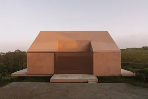 A pink house with a large open doorway, featuring a unique modern design and natural light