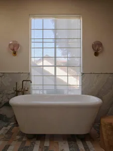 Bathroom with a large white bathtub under a window, surrounded by marble-like surfaces and white curtains, lit by natural sunlight