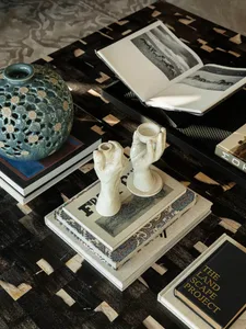 A casual coffee table scene with a blue vase, books, and a cup, arranged to create a cozy atmosphere