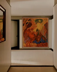 A room with a large, colorful painting of a woman on the wall, set against a carpeted floor and a doorway, creating a vibrant and artistic atmosphere