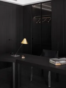 Cozy modern study with a wooden desk, metal accents, and a dimly lit atmosphere, featuring a couch and bookshelf