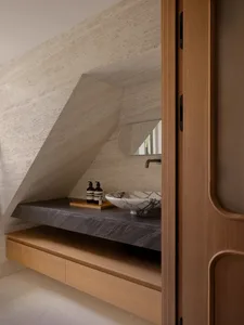 Modern bathroom with a slanted ceiling, a wooden cabinet, and a sink, featuring a practical and clean design