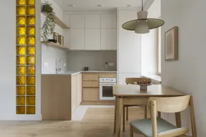 Warm and inviting kitchen and dining area with wooden cabinets, a wooden table, and chairs, set in a well-lit space with neutral colors and natural materials