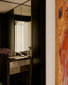 A well-lit black and white bathroom with a large mirror and a colorful vase on the sink