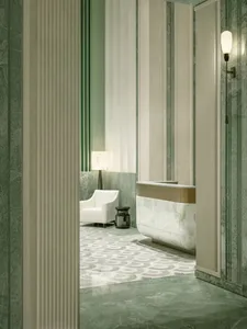 White bathroom with a green accent chair, sink, and bathtub in a dimly lit space