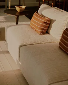 A well-lit living room with a white couch, a striped pillow, and modern furniture and decorations