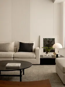Cozy modern living space with a white color scheme, a couch, chair, coffee table, and potted plant, featuring clean lines and simplicity