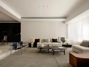 Cozy living room with a white couch, a chair, and a dining table, set against a dimly lit background