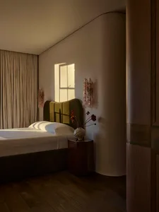 Cozy bedroom with a bed near a window, a vase with flowers on a table, and dim lighting