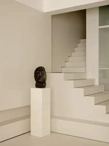 A photograph of a staircase with white marble steps, a black statue on a white pedestal at the bottom, and a sophisticated atmosphere