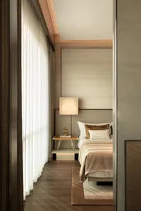 Cozy bedroom with a wooden floor, white curtain, and natural light from an open window