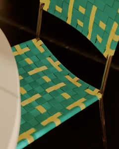 A wicker chair with a blue and yellow pattern sits on a white dining table in a casual dining area with natural lighting