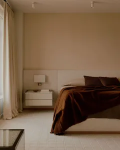 Cozy bedroom with a bed, nightstand, and lamp, surrounded by modern wood furniture and white walls, with natural sunlight coming through the window