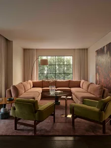 A living room with a couch, chair, and dining table arranged around a large window, creating a warm and inviting atmosphere with natural light