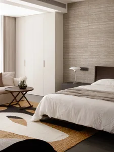 Cozy bedroom with a bed, couch, and table in a white color scheme, with natural light from a window
