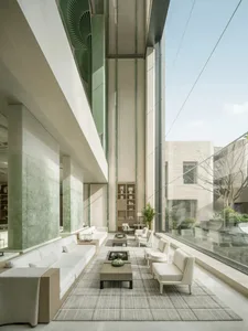 Large open living room with glass wall, furniture, potted plants, and vases, filled with natural light