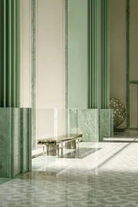 A bright and welcoming lobby with green walls, a glass door, a bench, and a dining table, with a vase on the right side