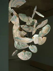 A modern room with a white color scheme, a minimalist design, and a dimly lit atmosphere, featuring a unique paper or fabric sculpture suspended from the ceiling