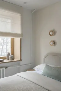 A well-lit bedroom with a bed, window, and lamp, featuring a cozy atmosphere and natural light