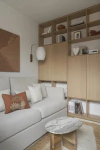 Cozy living room with a white couch, a gray chair, a bookshelf filled with books, and books scattered around the room, creating a warm and inviting atmosphere