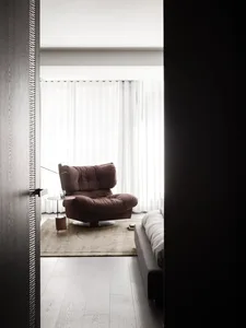 Dimly lit living room with a leather chair and fabric couch, a rug, and a cozy atmosphere