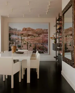 A modern dining room with a white table and chairs, surrounded by a vase, in a well-lit space with a bright and airy feel