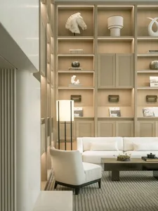 Comfortable living space with a white couch, chair, and wooden floor, filled with books and vases, and well-lit for a modern and inviting atmosphere