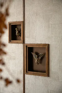 A warm and inviting wall with three wooden boxes containing pictures of angels in various poses, set against a tan background