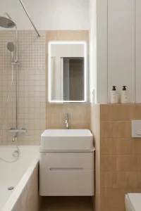 Bathroom with a white sink, mirror, and shower, set against a tiled background, with a minimalist and functional aesthetic