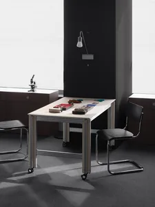 A dimly lit room with a white table and black chairs, featuring a book and a cup, creating a calm and inviting atmosphere for focused work