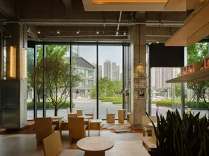 Modern restaurant with a large window, wood and concrete elements, and various pieces of furniture arranged to create a welcoming atmosphere