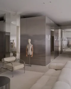 A modern living room with a mirrored wall, a couch, a chair, and a mannequin in a white dress, set in a well-lit space with a minimalist design