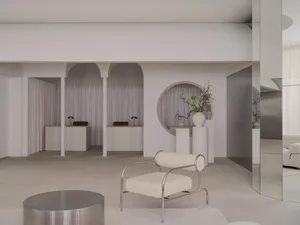 A spacious, modern room with a circular wall, various furniture pieces, and a large window allowing natural light