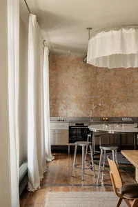 A modern kitchen with a dining table and chairs, surrounded by a wooden floor, sink, and neutral color palette