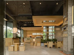 Modern restaurant with a warm atmosphere, featuring wood and concrete elements, multiple seating options, and well-designed lighting