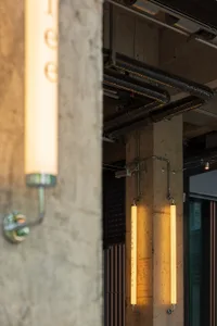 Dimly lit industrial space with a concrete floor and a pipe running along a concrete wall