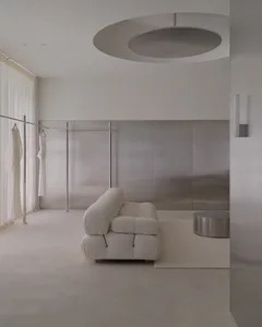 A modern living room with a white couch and chair, decorated with white furniture and a silver-toned appearance, in a well-lit and inviting atmosphere