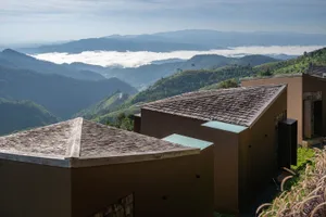 Photograph of a mountainous area with wooden houses built on a hillside, surrounded by mountains and natural scenery