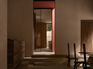 Dining room with a red doorway, a window, and a bench, featuring a combination of wood and stone elements, with a warm and inviting atmosphere