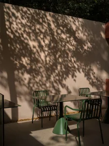 餐廳戶外天井區，桌椅環繞混凝土牆，背景有餐桌，暖意氛圍與自然日光