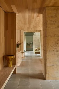 Cozy living room with a stone wall, wooden floor, a couch, a sink, and a vase, lit by natural light