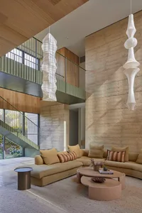 Comfortable living space with a couch, chair, coffee table, and pillows, featuring a large window for natural light and soft, diffused lighting