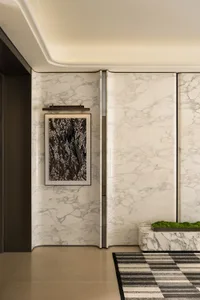 Bathroom with a white marble wall, a door, and a toilet, set in a dimly lit space with an intimate atmosphere