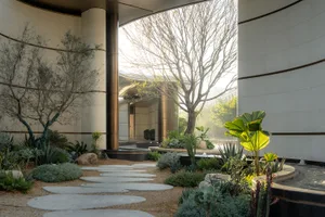 一棟現代建築搭配寬敞花園，園內有樹木，四周綠意盎然且自然光線充足