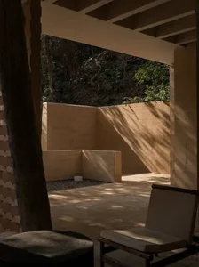 A stone-walled outdoor living space with a bench and chair, inviting relaxation and socializing