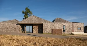 Photograph of a rustic cabin with a wooden exterior, featuring a unique design with a sloping roof and a cozy atmosphere