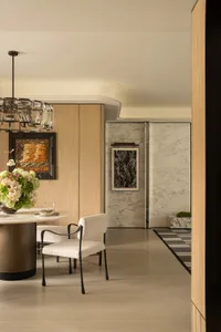 Modern dining room with a chandelier, dining table, chairs, and a potted plant, set for a meal or gathering