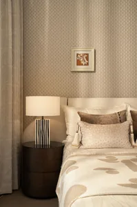 Cozy bedroom with a white comforter, a bedside lamp, and a framed artwork on the wall