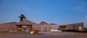 A rustic building with a combination of wood and stone materials, featuring a large window on the upper floor, providing natural light and a welcoming atmosphere