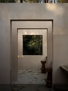 Dimly lit bathroom with concrete walls, two toilets, and a window allowing natural light